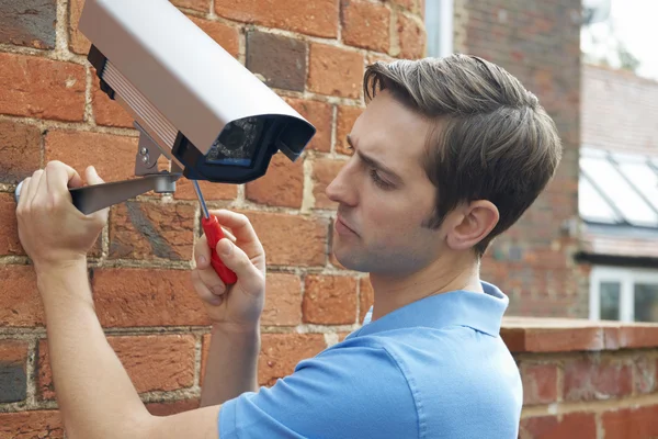 Mann montiert Überwachungskamera an Hauswand — Stockfoto