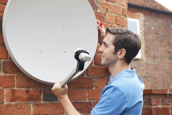 Muž, který odpovídá Tv satelit na zdi domu — Stock fotografie