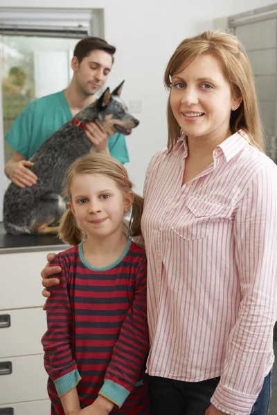 Mor och dotter med hund för undersökning på veterinärer — Stockfoto