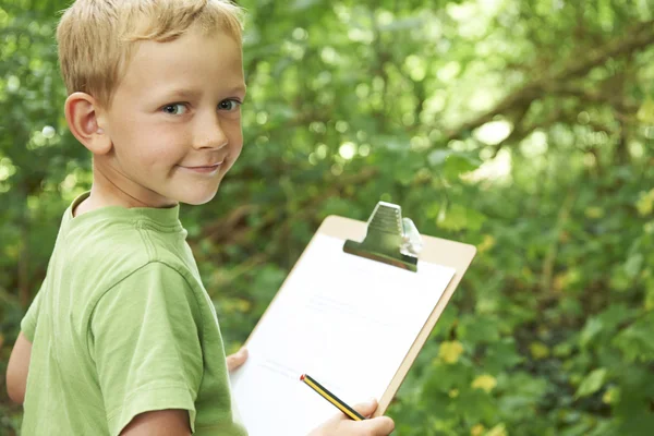 Мальчик делает заметки на школьной экскурсии по природе — стоковое фото