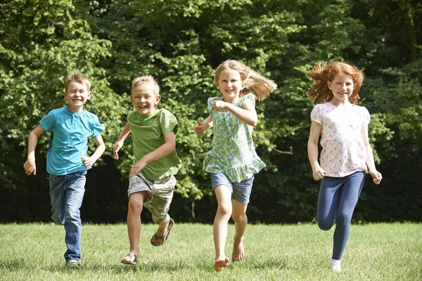 Kindergruppe läuft mit Handtuch-Kamera auf Spielplatz — Stockfoto