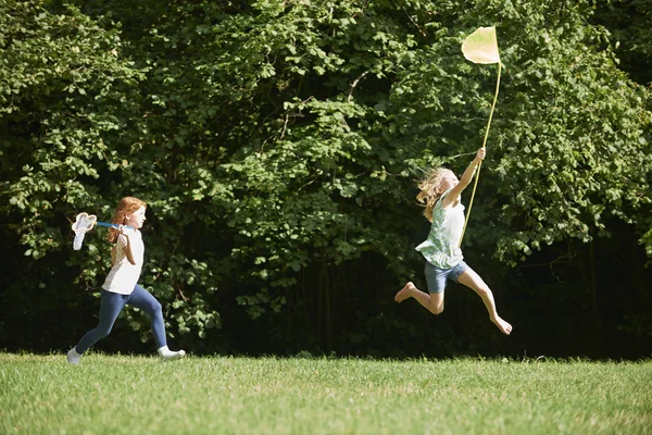 Duas meninas perseguindo borboletas no campo de verão — Fotografia de Stock