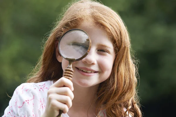 Ragazza guardando attraverso lente di ingrandimento con occhio ingrandito — Foto Stock