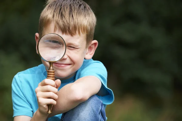 Jongen op zoek door vergrootglas met vergrote oog — Stockfoto