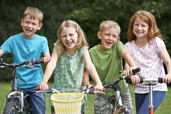 Groupe d'enfants jouant sur des vélos et un scooter — Photo