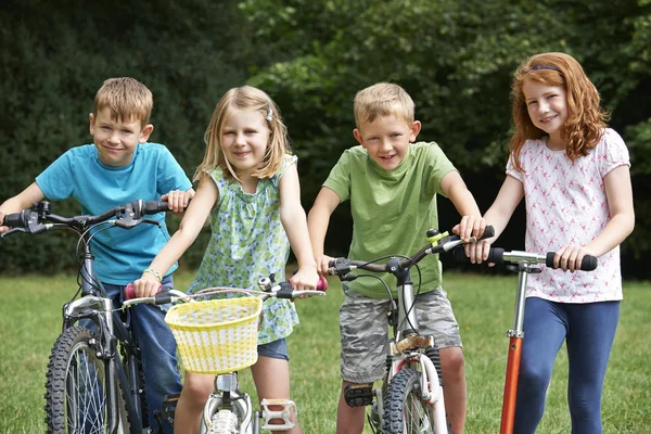 Groupe d'enfants jouant sur des vélos et un scooter — Photo