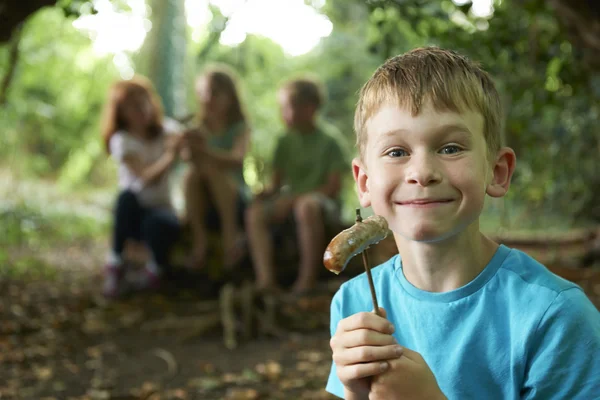 Pojken äta korv runt Camp med vänner — Stockfoto