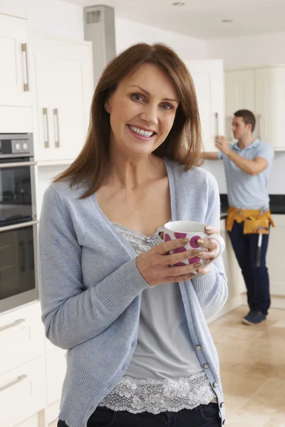 Frau steht mit Arbeiter in neuer Einbauküche — Stockfoto