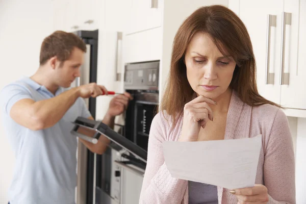 Woman Looking Concerned At Bill For Repair Of Kitchen Appliance — Stock Photo, Image