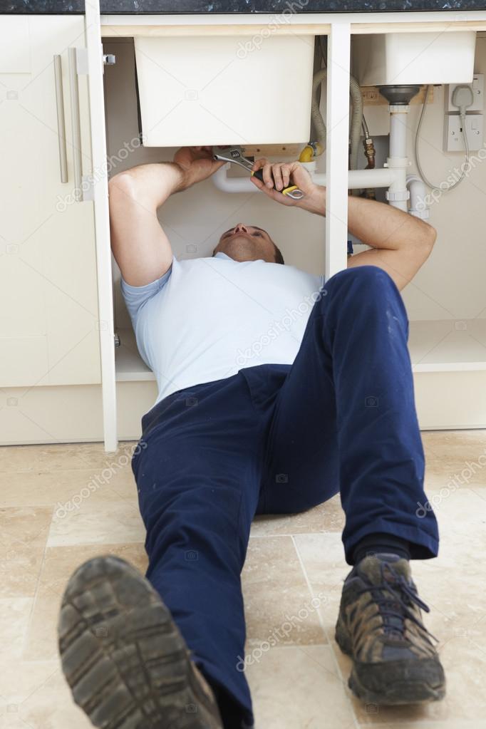 Plumber Working Under Sink With Wrench