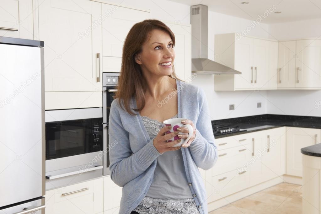 Woman Standing In New Luxury Fitted Kitchen