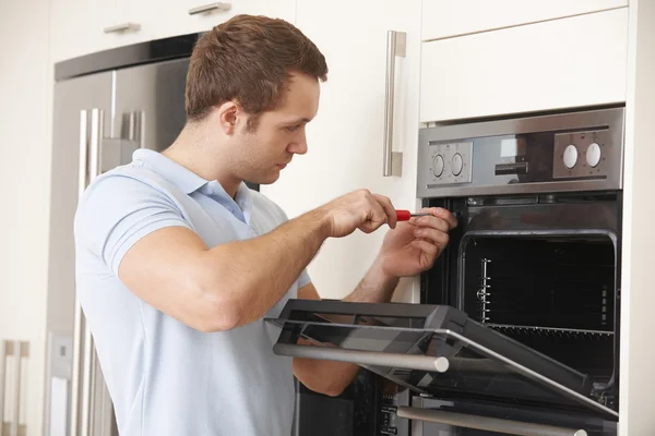 Hombre reparando horno doméstico en la cocina —  Fotos de Stock