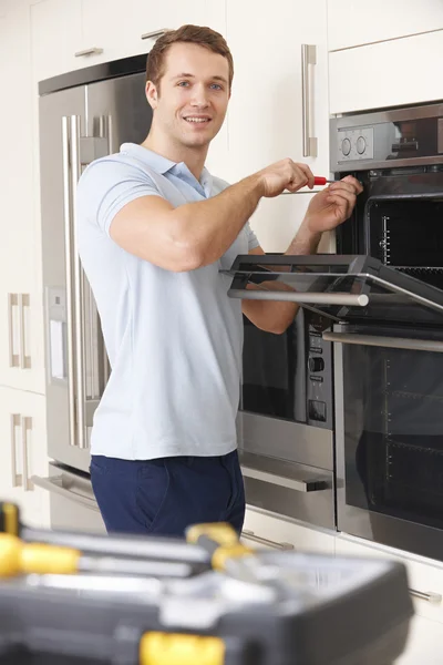Homem que repara o forno doméstico na cozinha — Fotografia de Stock