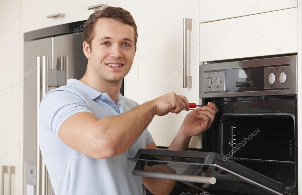Engineer Reapiring Domestic Oven In Kitchen