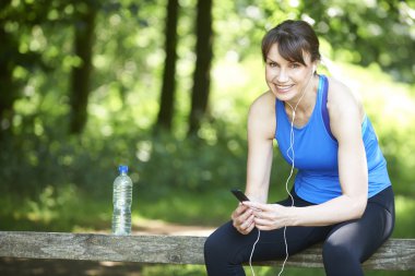 Orta yaşlı kadın rahatlatıcı Mp3 Player ile egzersiz sonrası