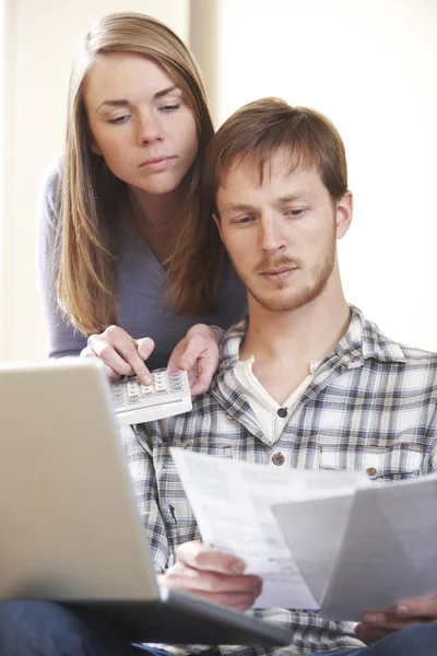 Серьезные молодые пары смотрят на домашние финансы — стоковое фото