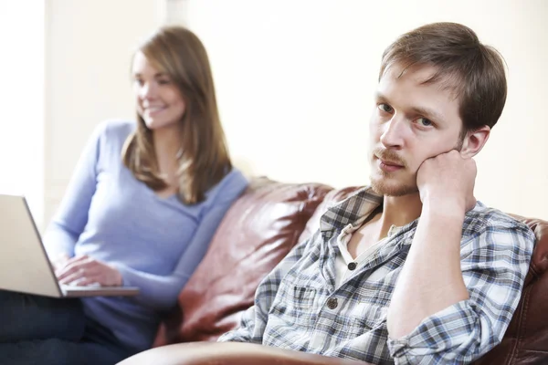 Unhappy Man Sitting On Sofa As Partner Uses Computer — Stock Photo, Image