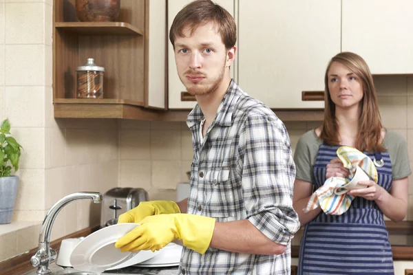 Hombre a regañadientes lavándose en la cocina con su pareja — Foto de Stock