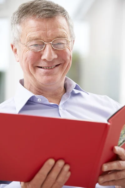 Usměvavá starší muž při pohledu na Album fotografií — Stock fotografie
