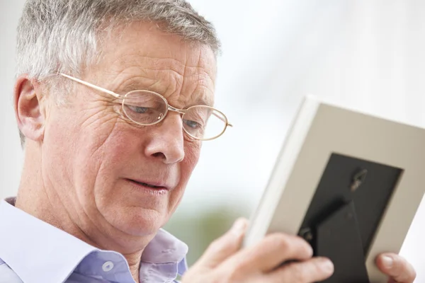 Ongelukkige Senior Man kijken naar foto In Frame — Stockfoto