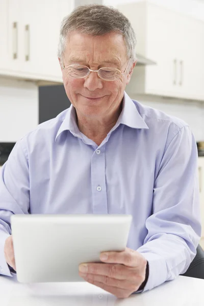 Homem sênior usando tablet digital em casa — Fotografia de Stock