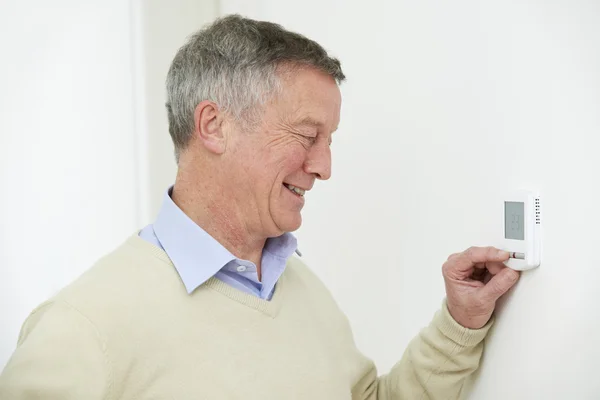 Senior Man Adjusting Central Heating Thermostat — Stock Photo, Image