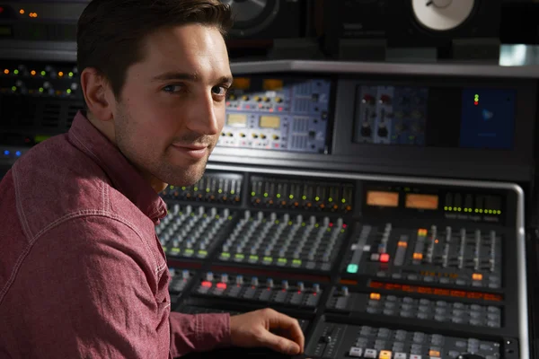 Engineer Sitting At Mixing Desk In Recording Studio