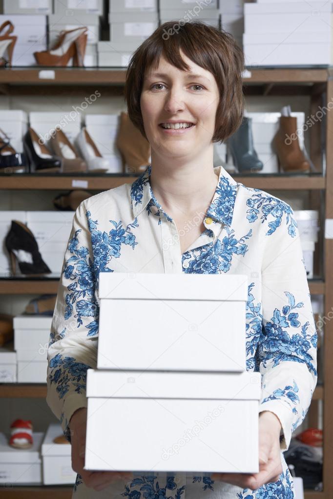Female Owner Of Shoe Store Carrying Boxes