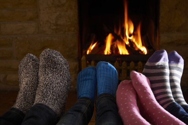 Family Warming Feet By Fire