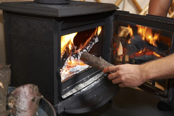 Man Putting Log Onto Wood Burning Stove — Stock Photo, Image