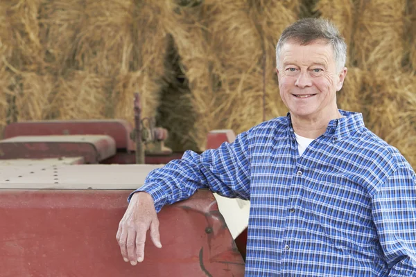 Farmář, stojící před balíků a staré zemědělské stroje — Stock fotografie