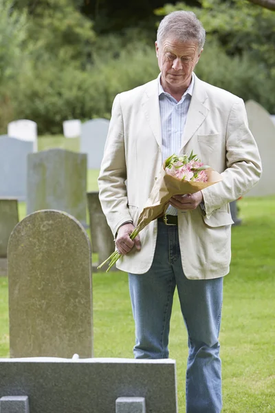 Man tot vaststelling van bloemen op graf — Stockfoto