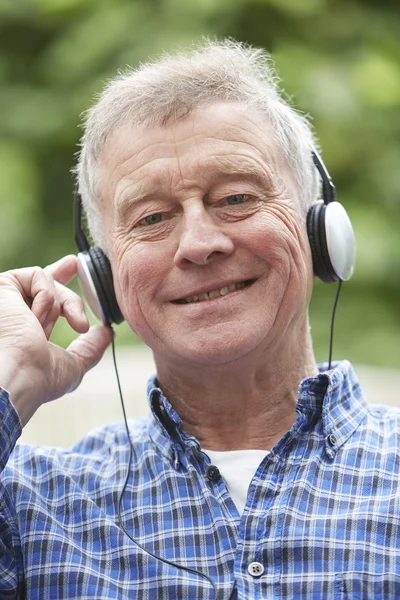 Ανώτερος άνθρωπος χαλάρωση ακούγοντας μουσική στα ακουστικά — Φωτογραφία Αρχείου