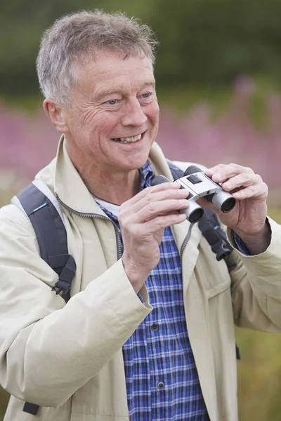 Senior Man op wandeling met een verrekijker — Stockfoto