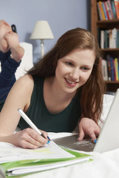 Adolescente utilisant un ordinateur portable pour faire des devoirs dans la chambre — Photo