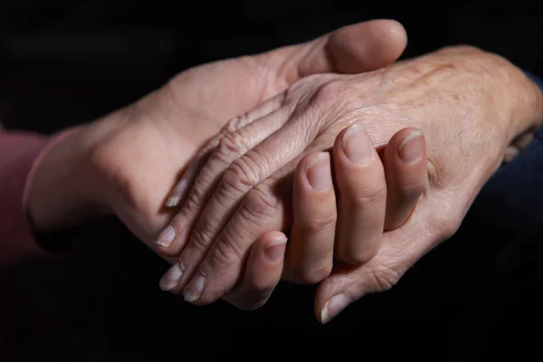 Mujer joven sosteniendo la mano de una mujer mayor — Foto de Stock