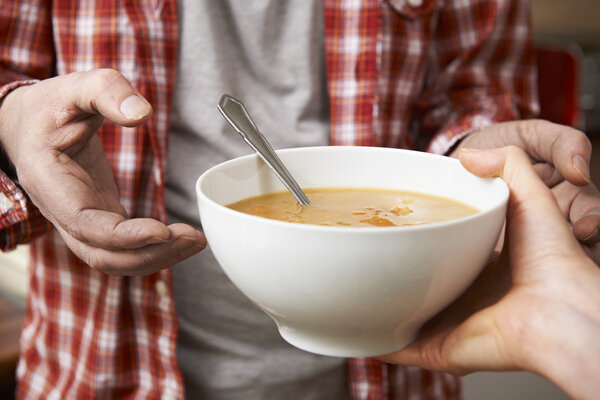 Homeless Man Being Handed Bowl Of Soup By Volunteer