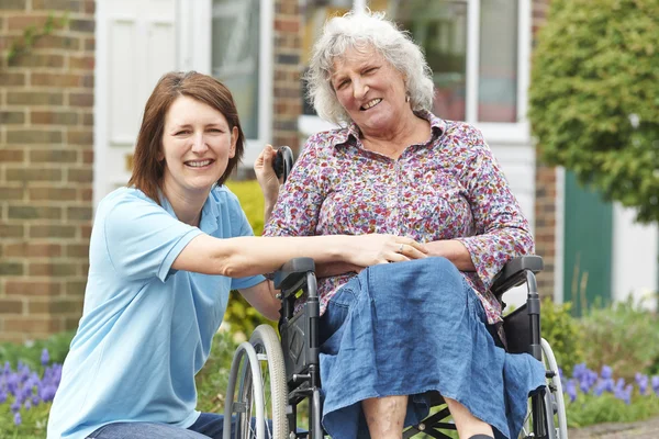Vårdare med äldre kvinna i rullstol — Stockfoto