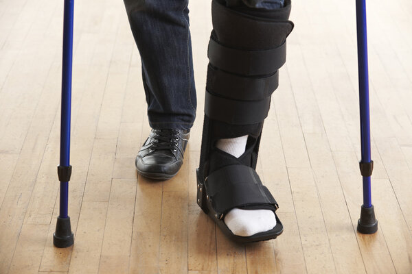 Закрыть человека, идущего с касками и в гипсе
