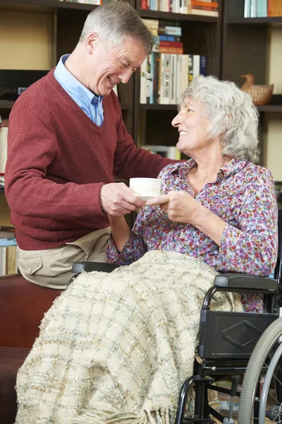 Ανώτερος άνθρωπος, δίνοντας τη σύζυγό του σε αναπηρικό καροτσάκι φλιτζάνι τσάι — Φωτογραφία Αρχείου