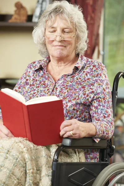 Starší žena v vozíku čtení knihy — Stock fotografie