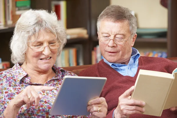 Pareja mayor usando tableta digital y libro de lectura — Foto de Stock