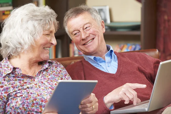 Coppia anziana che utilizza tablet e laptop digitali a casa — Foto Stock