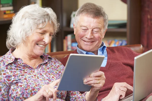 Старшая пара с помощью цифрового планшета и ноутбука дома — стоковое фото