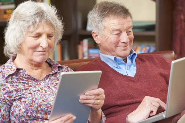 Seniorenpaar nutzt digitales Tablet und Laptop zu Hause — Stockfoto