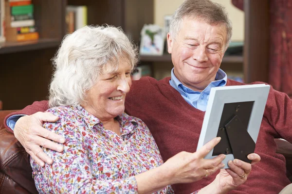 Pareja mayor mirando la fotografía en el marco juntos —  Fotos de Stock