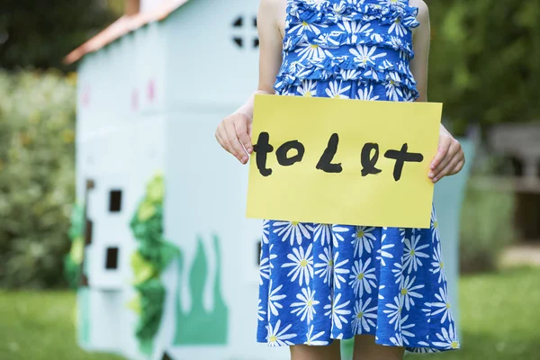 Little Girl Holding To Let Sign Outside Play House — Stock Photo, Image