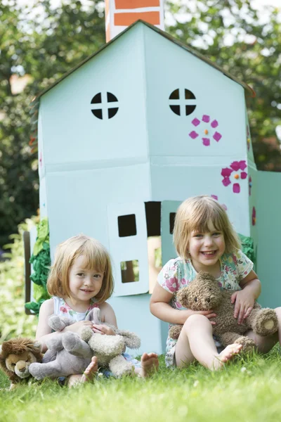 Duas crianças brincando em casa feita casa de papelão — Fotografia de Stock