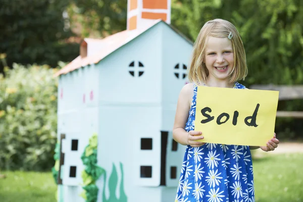 Little Girl Holding Sold Sign Outside Cardboard Playhouse — Stock Photo, Image