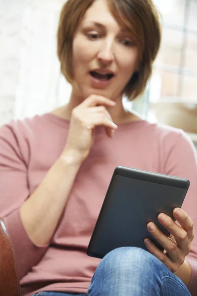 Mujer conmocionada leyendo el libro electrónico en casa — Foto de Stock